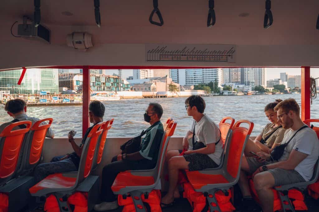 Passengers seated inside a Chao Phraya River ferry with orange seats