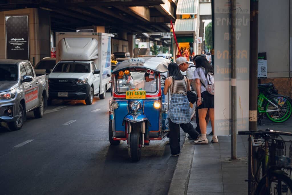 Passengers getting into a tuk-tuk on a Bangkok street