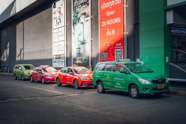 Green and red taxis lined up outside a shopping mall in Bangkok