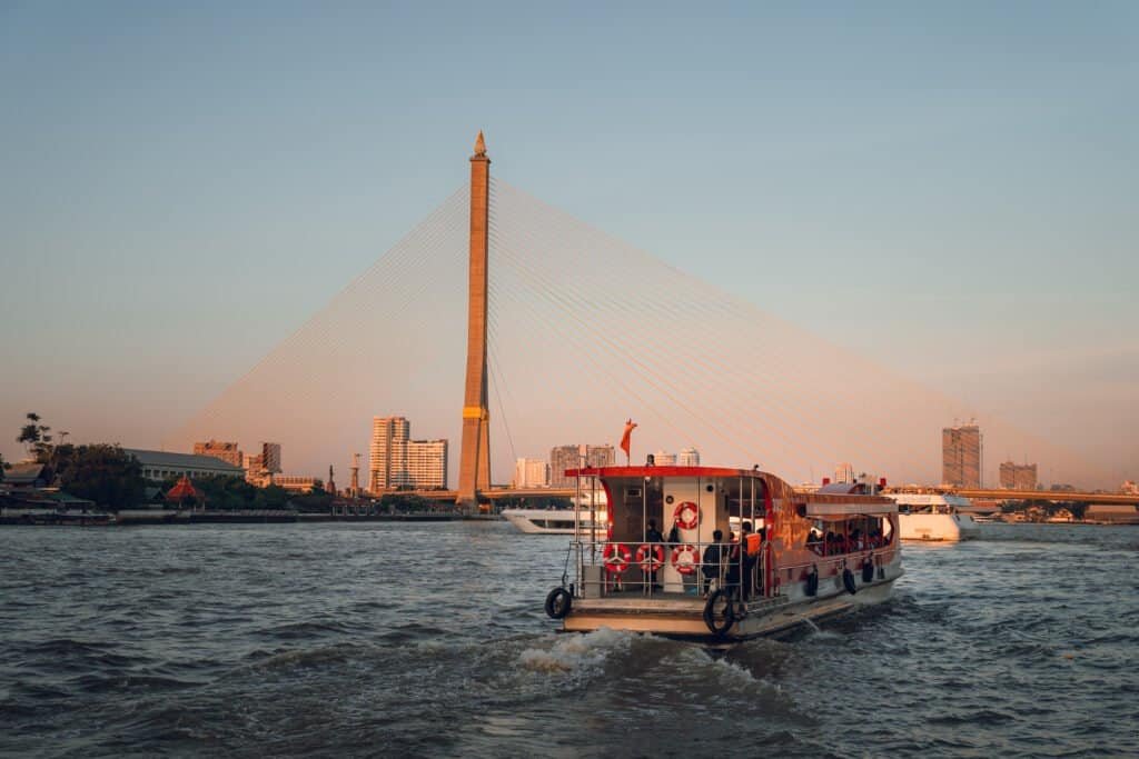 River boat passing Rama VIII Bridge on the Chao Phraya River in Bangkok